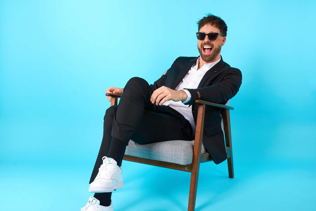 Man zitting on chair and wearing black men's suit and sunglasses