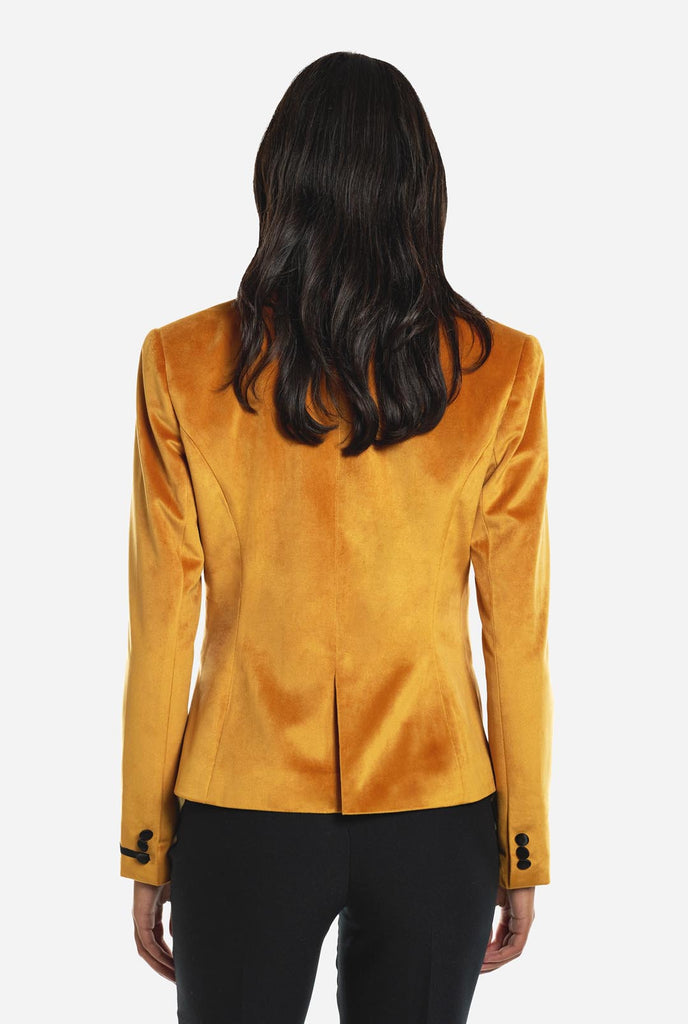 Woman wearing golden velvet dinner jacket blazer, view from the back