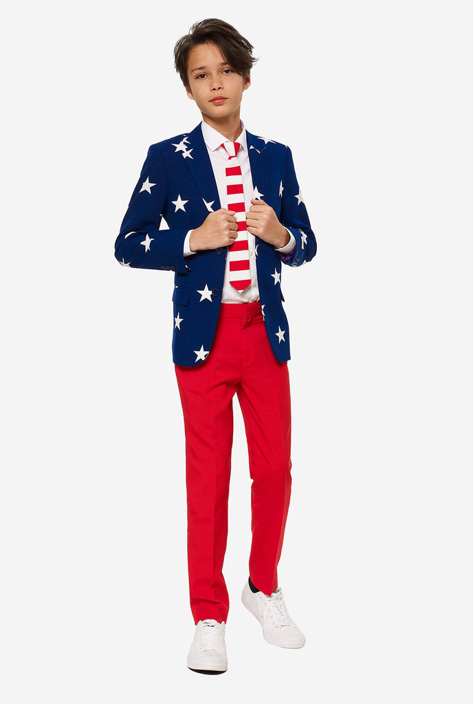 Teen wearing formal USA themed fourth of July suit, consisting of blue jacket and red pants. 